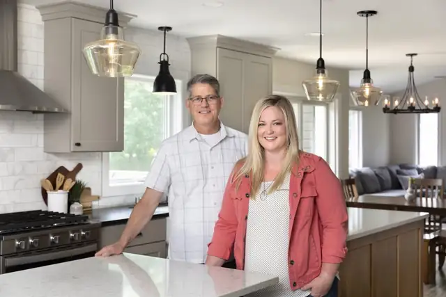 Co-owners Steve McDonald and Angela Barnhart standing at a kitchen island with glass pendant lights