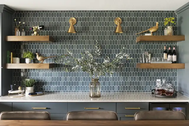 Lakeville lower level home bar with blue-gray elongated hexagon tile, floating wood shelves and brass sconces