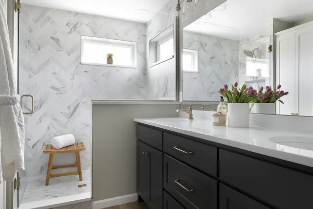 Eagan primary bath with herringbone marble tile shower, teak bench and navy double vanity