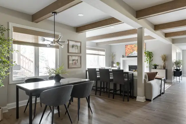 Rosemount basement remodel with painted ceiling beams, dining table, bar seating and modern black chandelier