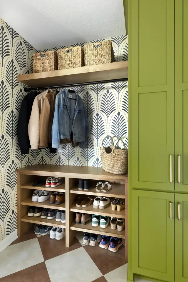 Lakeville mudroom remodel with palm-pattern wallpaper, open coat hooks, wood shoe shelves under a bench and green cabinets