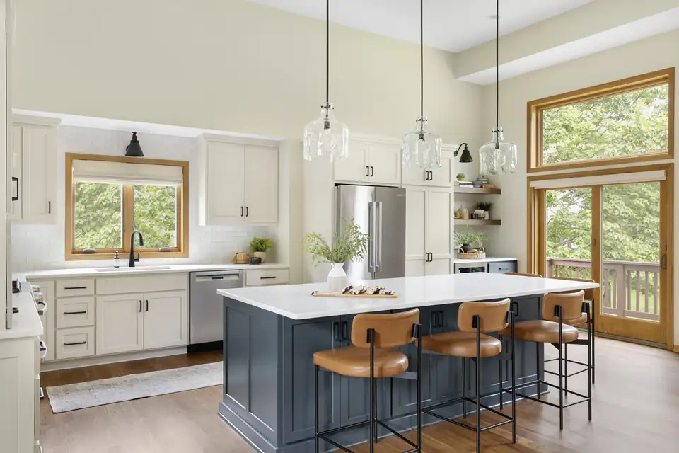 Kitchen remodeling Lakeville MN by White Birch Design: white cabinets, navy island with leather counter stools, glass pendants and wood-trimmed windows
